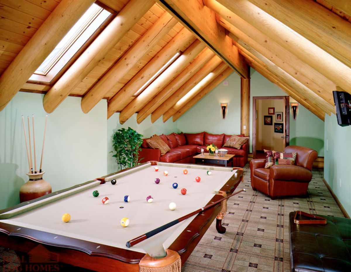 pool table under rafters of log cabin loft