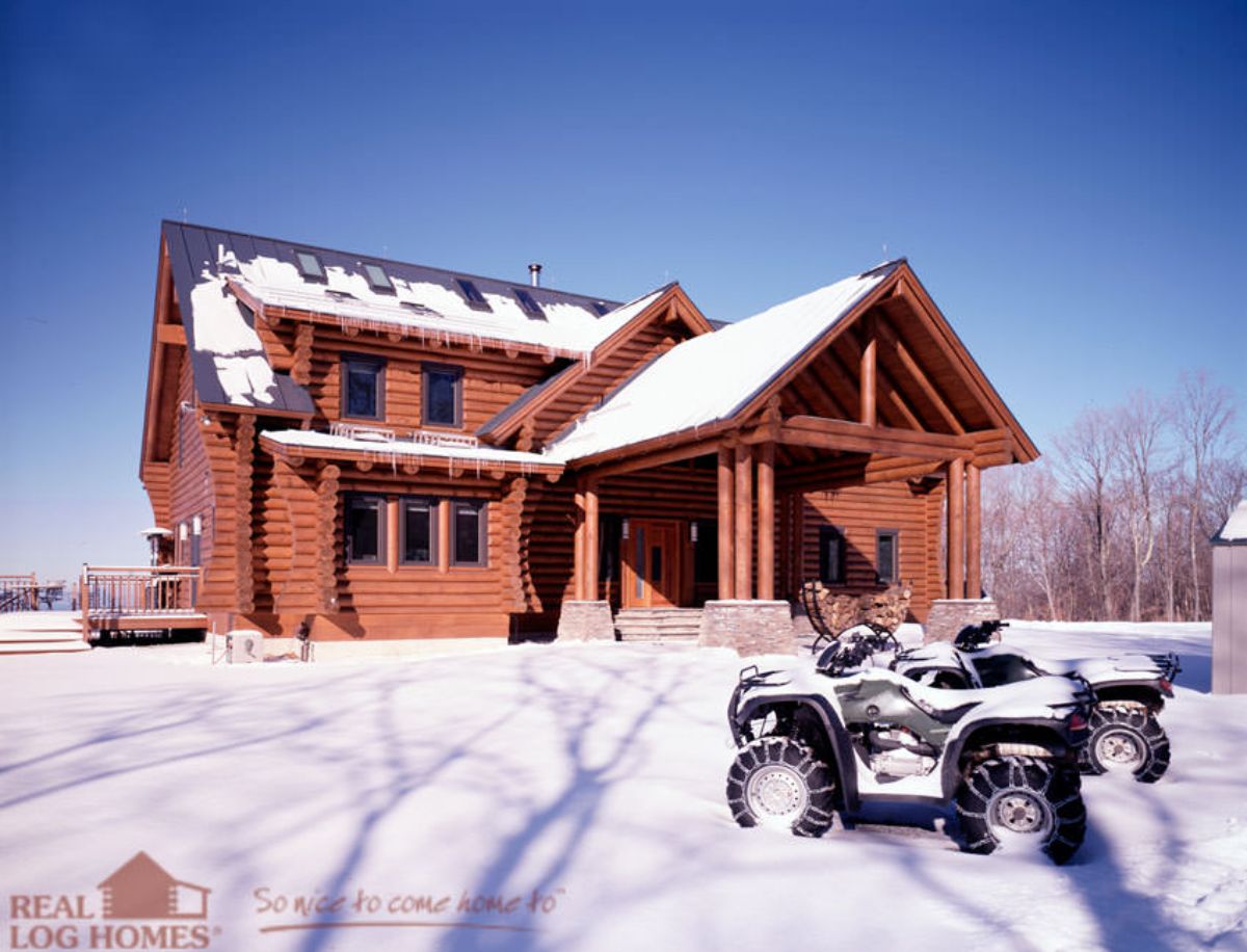 log cabin with small covered porch in the snow