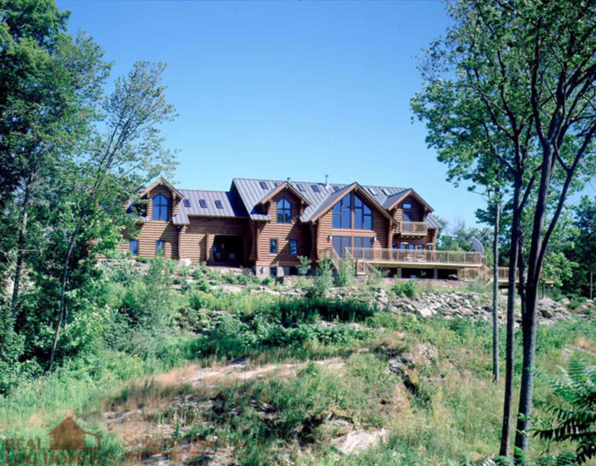 log cabin on hill behind green yard