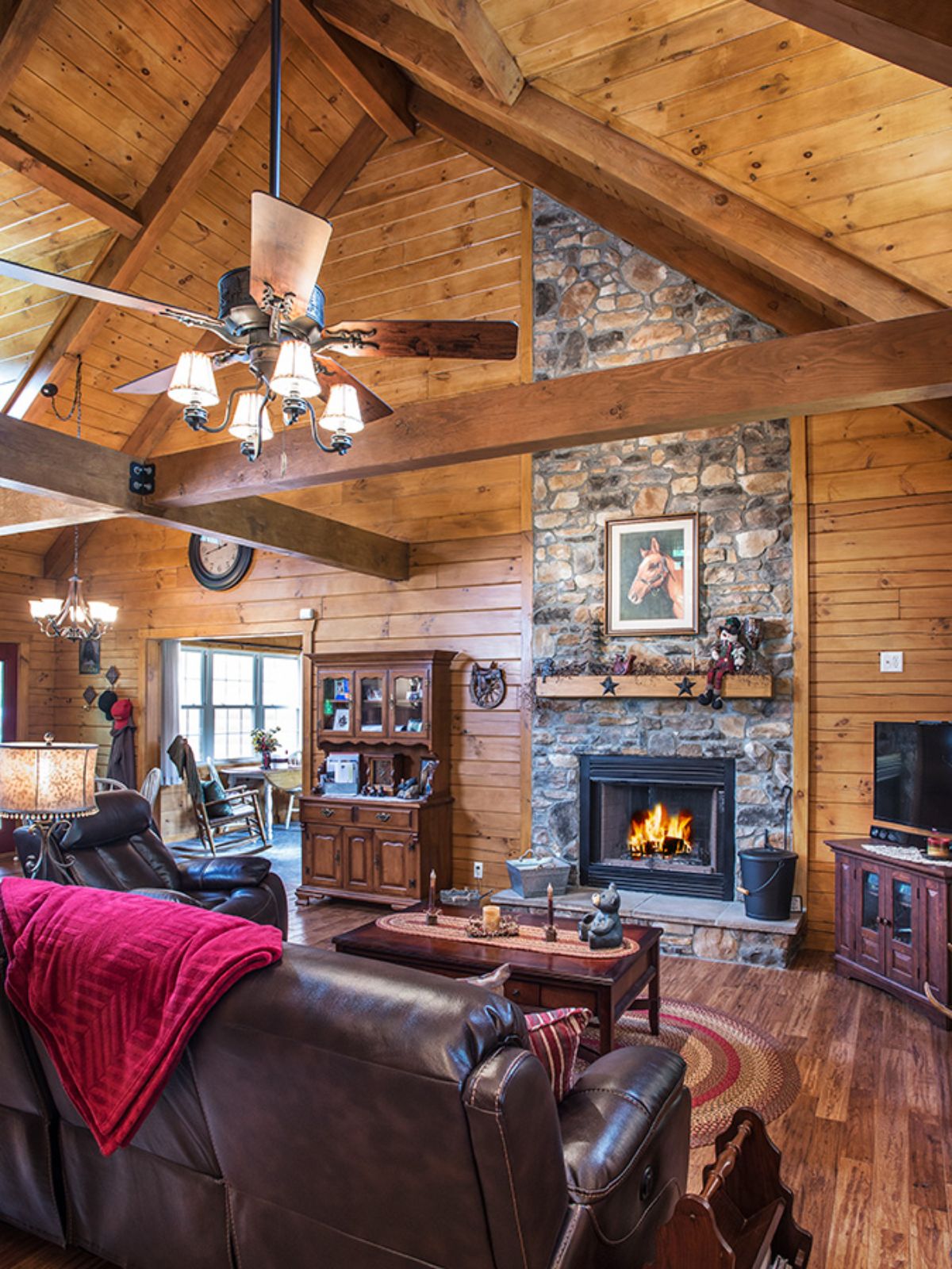 stone fireplace against log cabin wall with opening to dining room on left