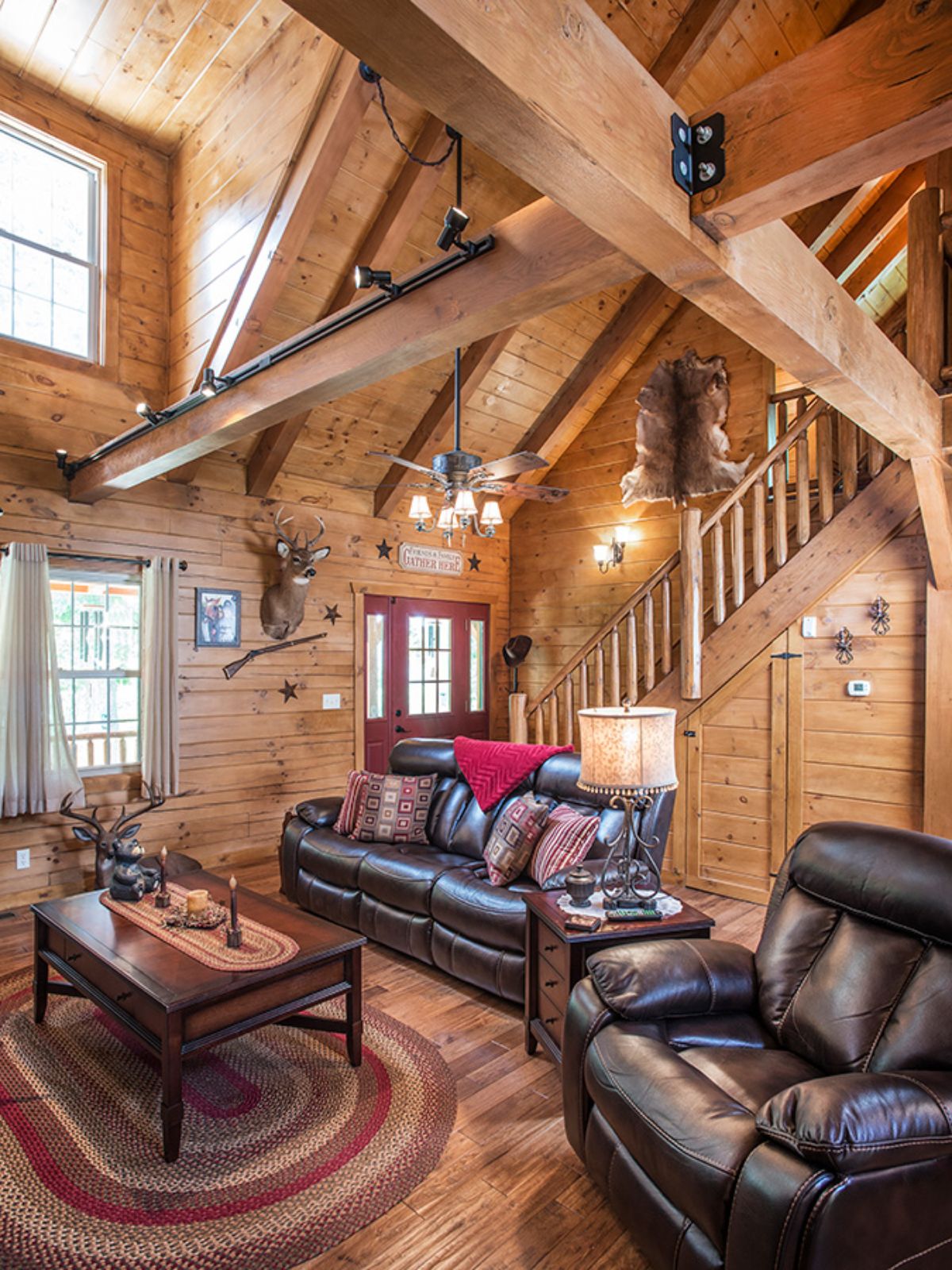 black leather sofas in living space under cathedral ceiling of log cabin