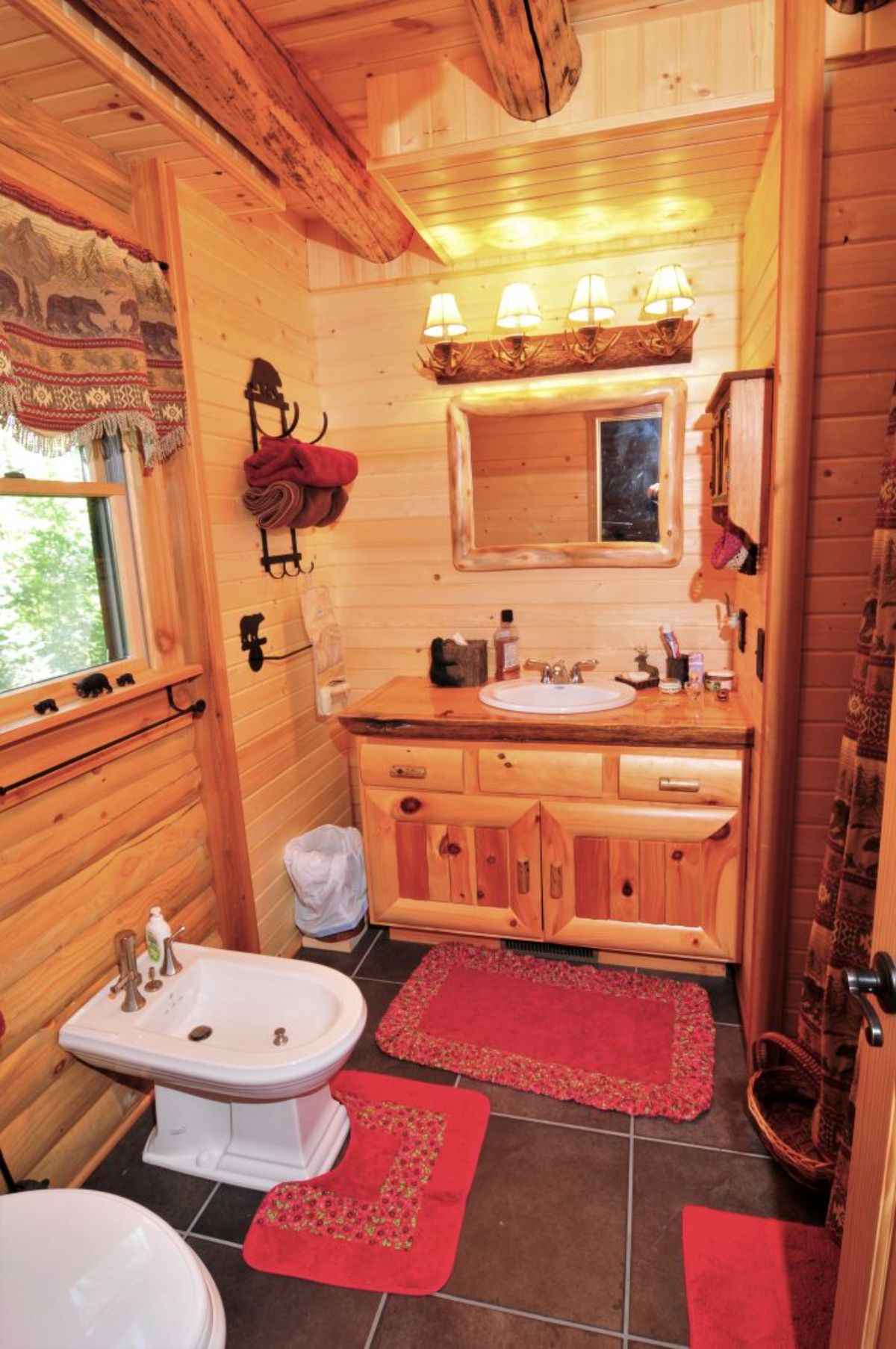 red rug on floor in front of bidet with light wood cabinet under mirror