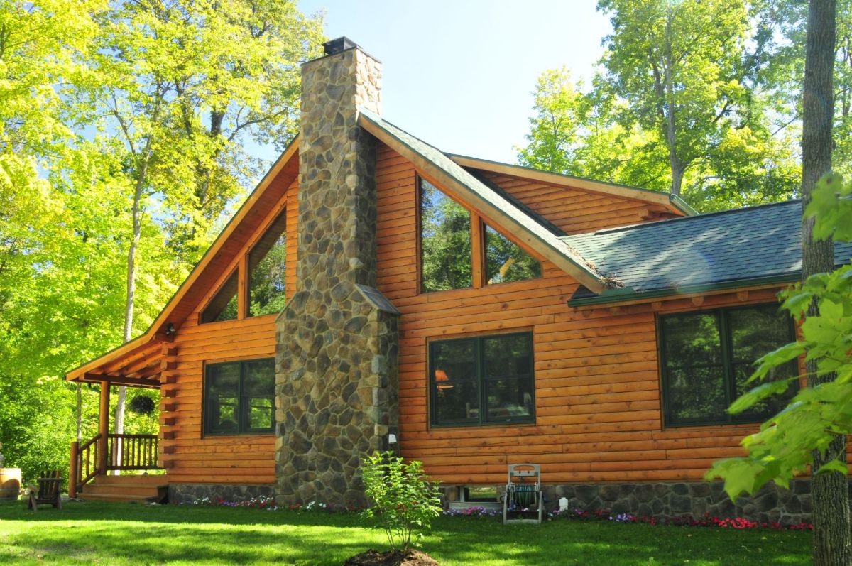 end of log cabin showcasing windows on both sides of the stone chimney