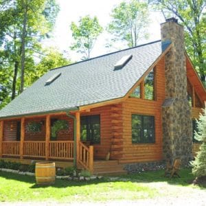 light stain on log cabin with covered porch on the front and stone chimney on the side