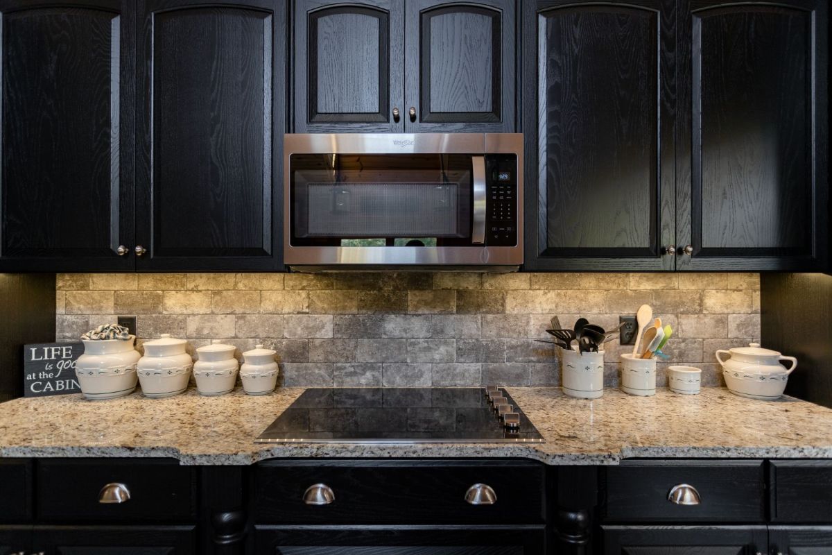 stove in granite counter with black cabinets and microwave above stove