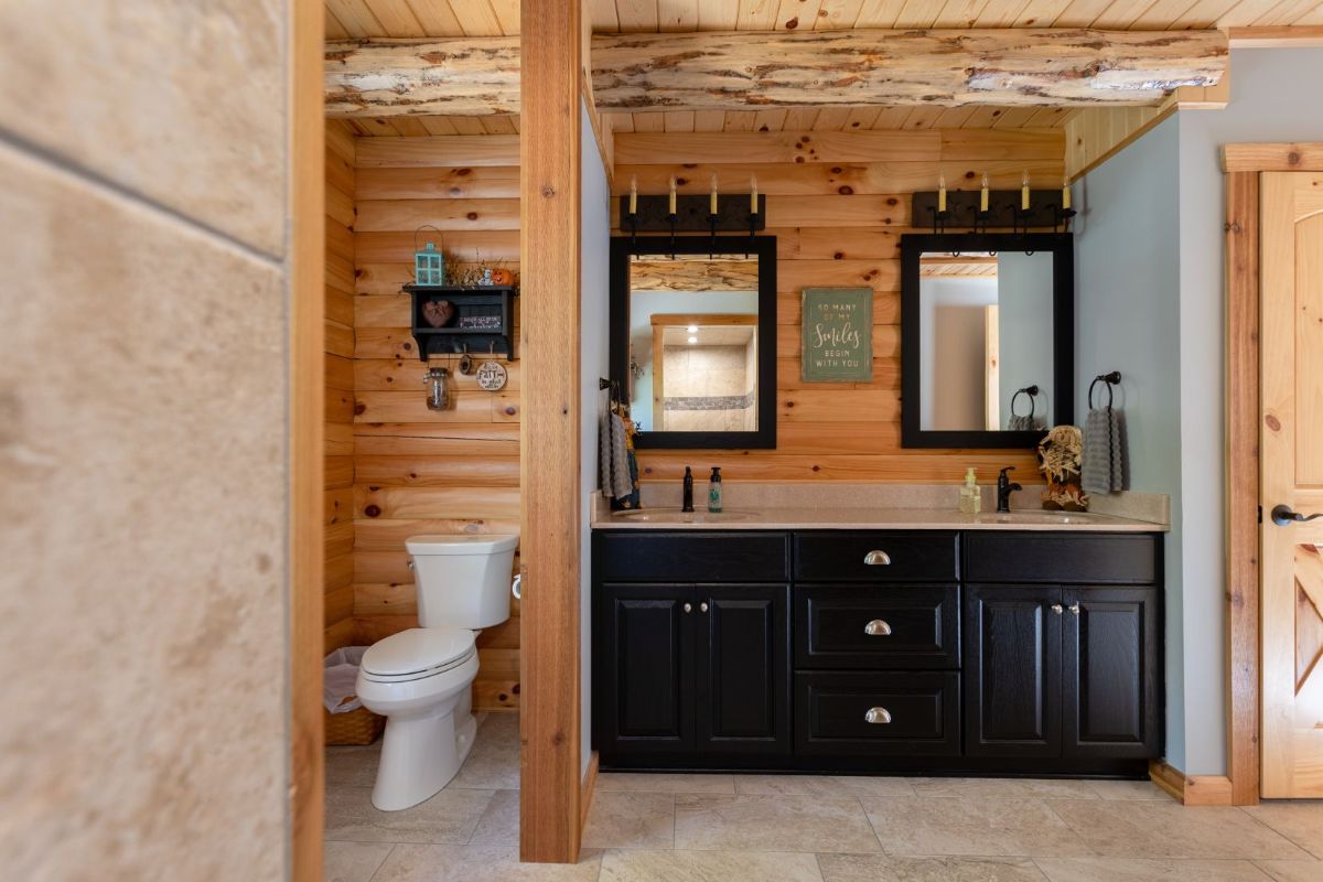 white toilet on left by wall next to dark wood vanity with two mirrors