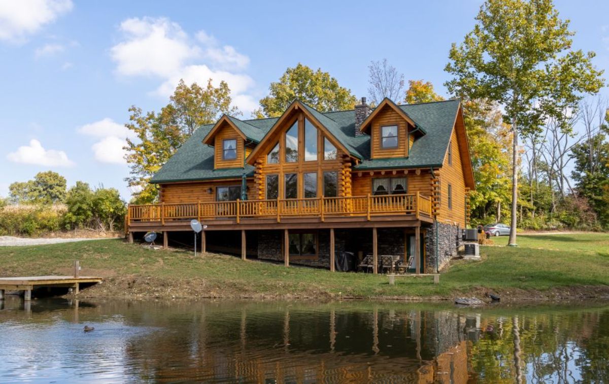 view of pond and back of log cabin with open deck