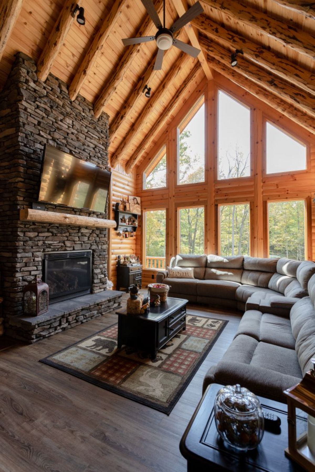 sectional sofa across from stone fireplace with wall of windows on right