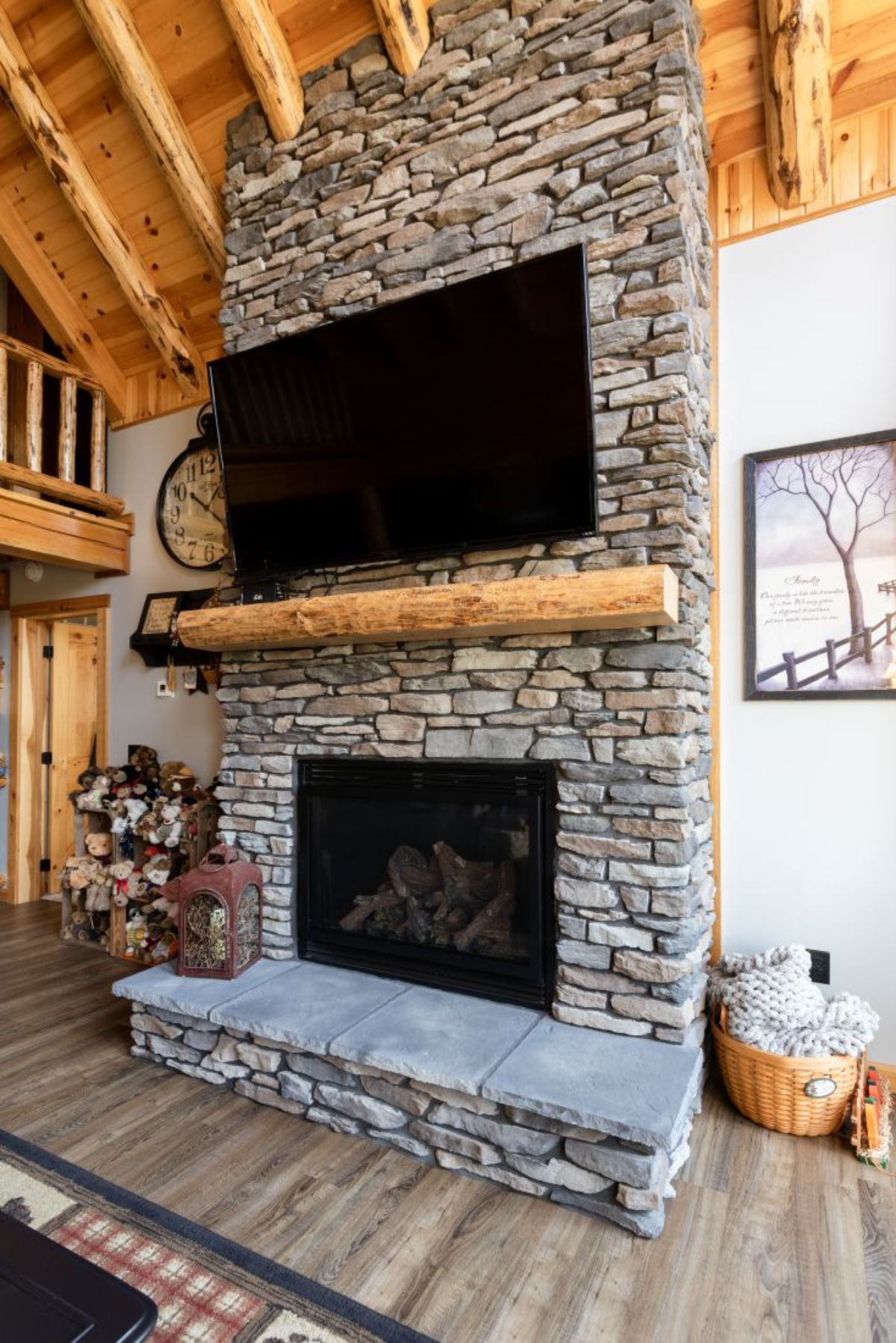 stone fireplace with light wood log mantle and mounted television above mantle