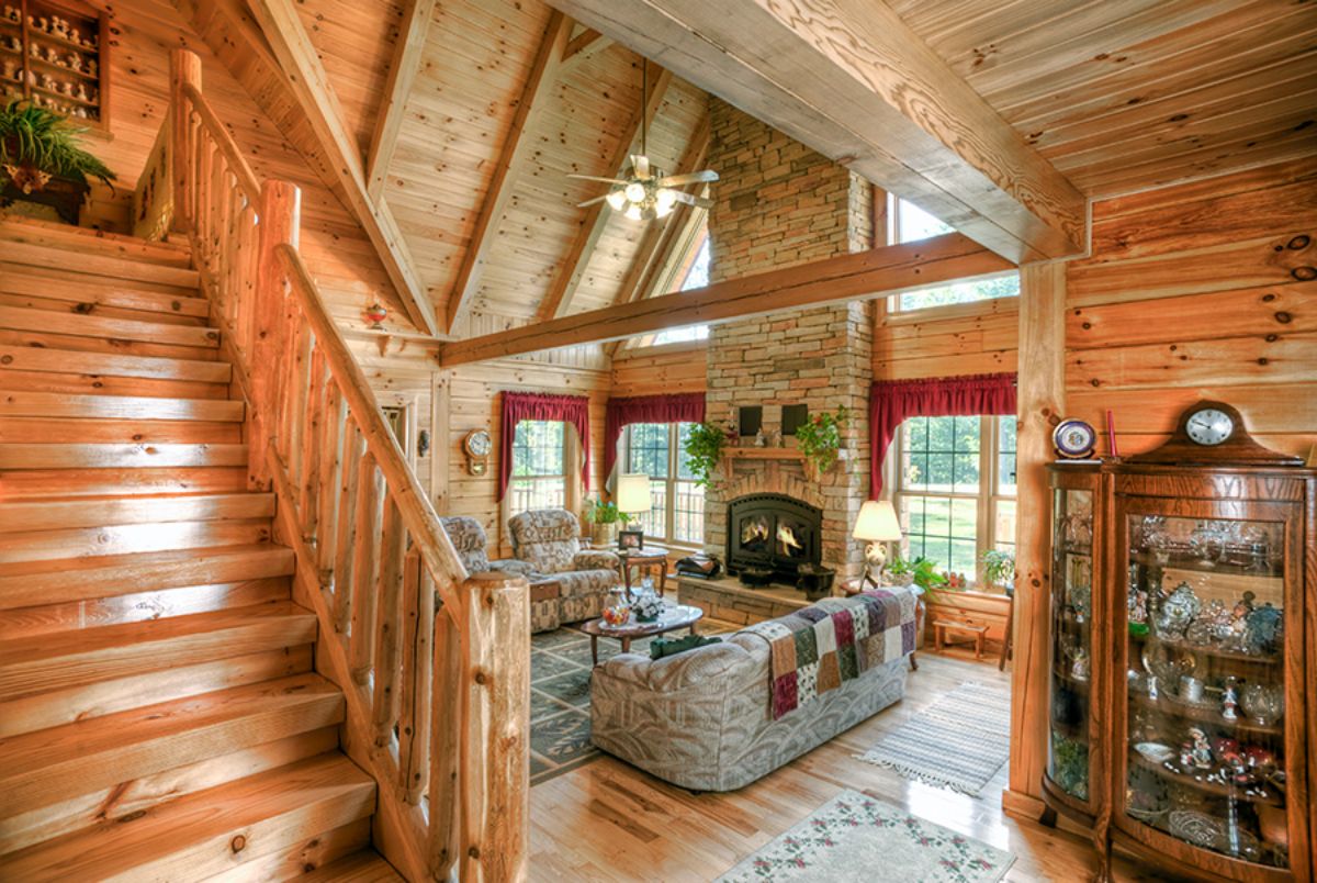 view into great room of log cabin with stairs on left of image
