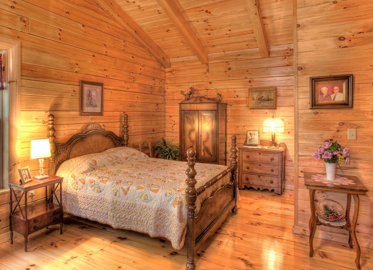 wood bed frame with cream bedding with log walls ceiling and floor