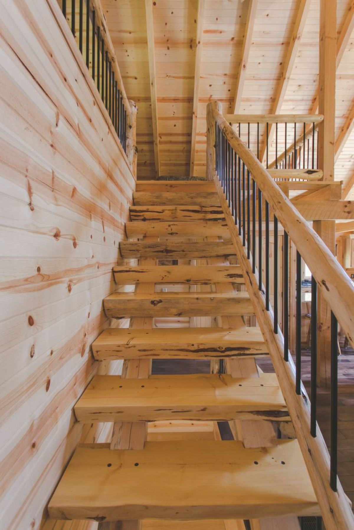 view up log stairs to loft with black spindles on rails