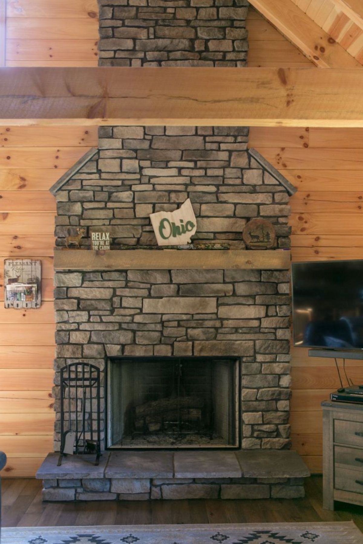 stone fireplace with ohio sign above log mantle