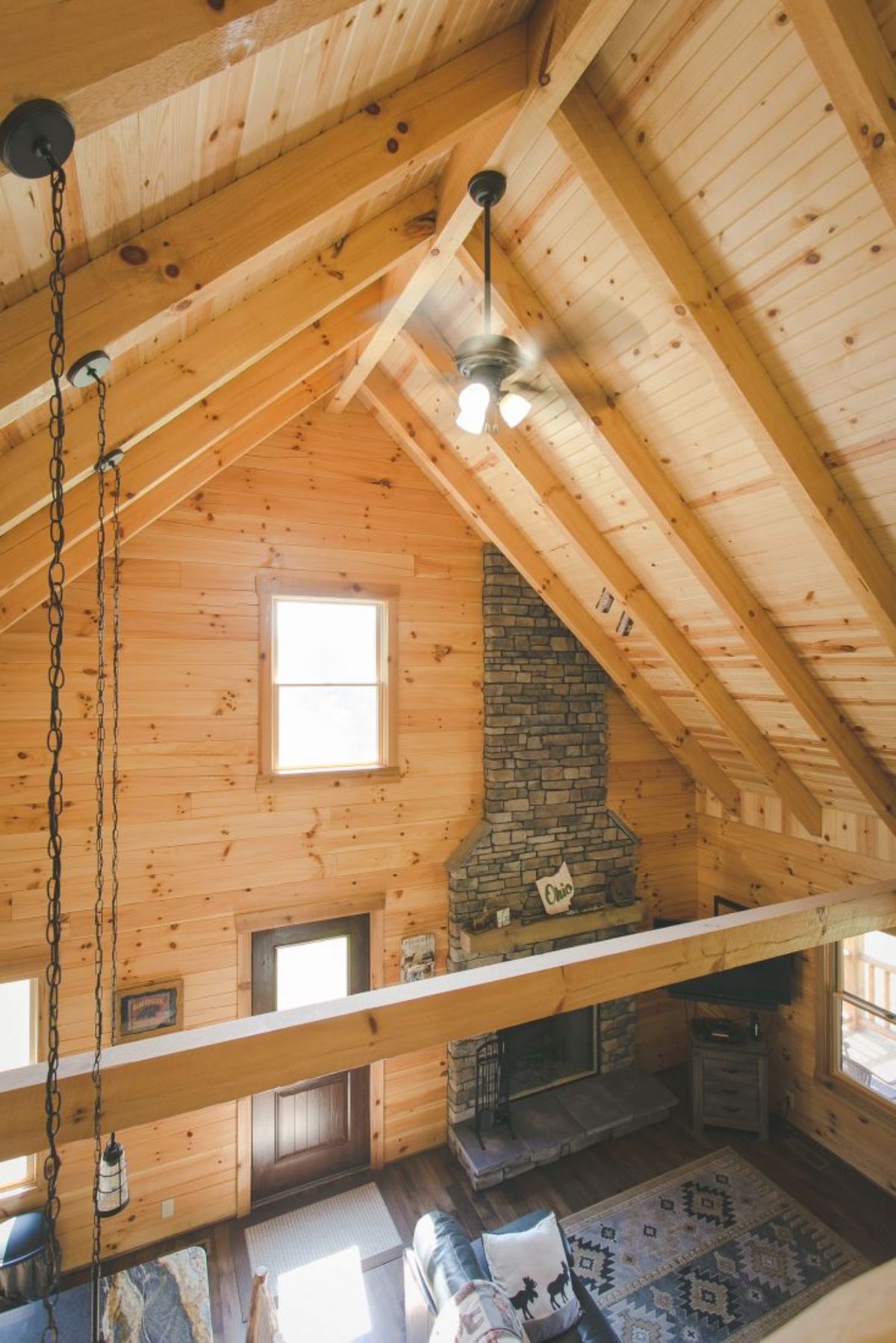 view across cathedral ceiling in log cabin showing stone fireplace on right side