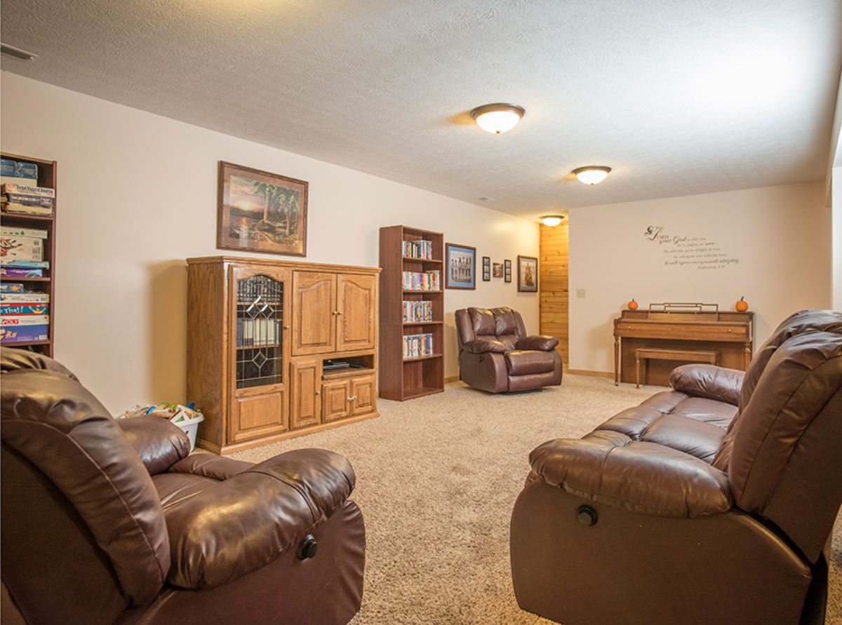 brown leather sofa in basement with white walls and ceiling