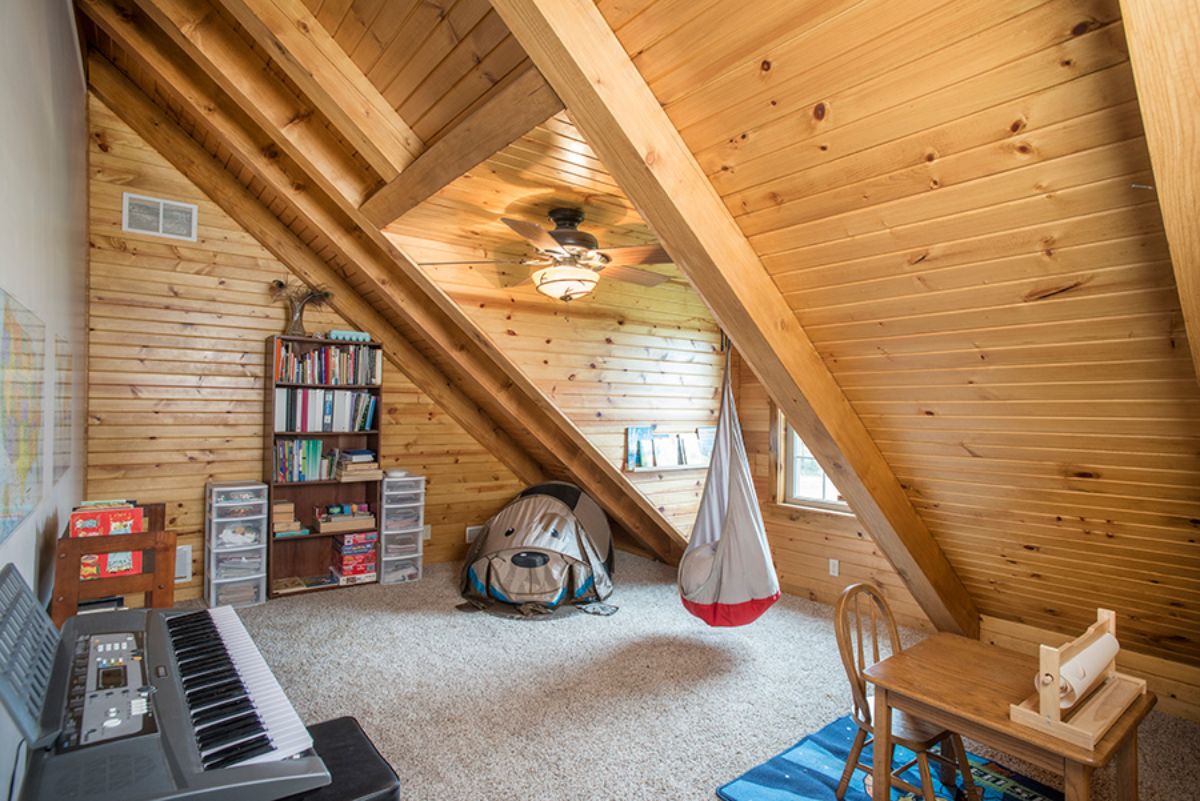 angled eave in bedroom with hanging chair in dormer window space and keyboard in foreground