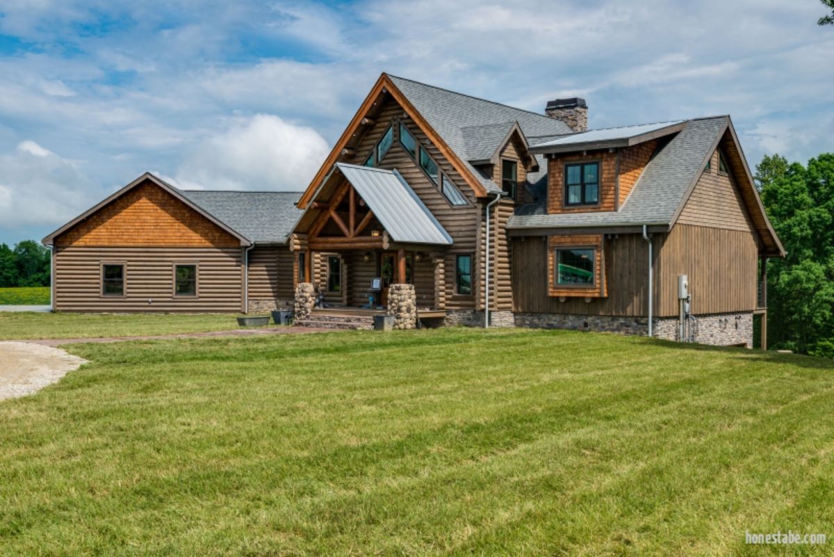 side of log cabin with attached garage and green yard