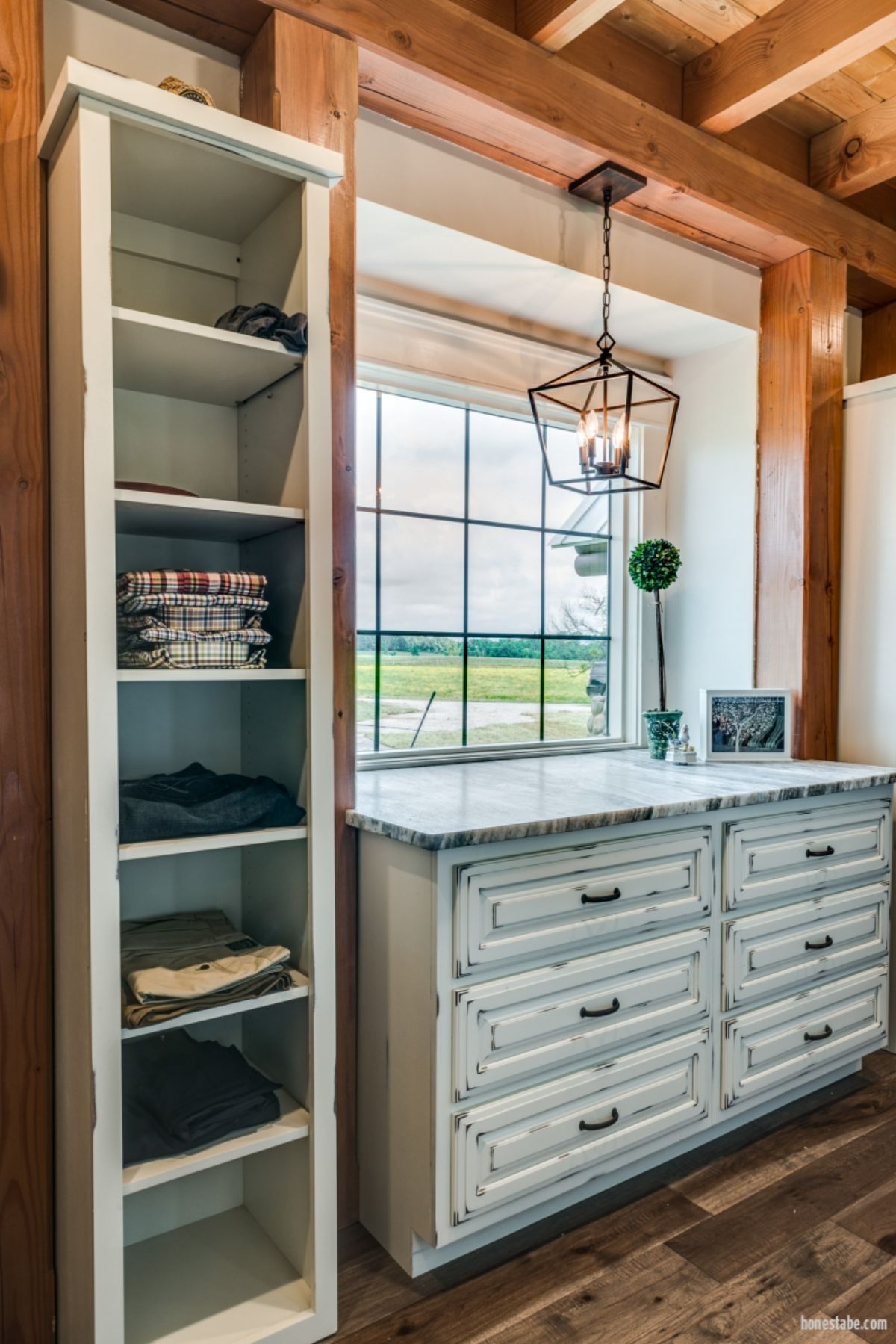 open shelves in closet with white washed chest of drawers below window