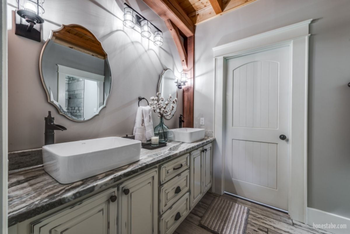 white wood vanity with two white bowl sinks and round mirrors against left wall