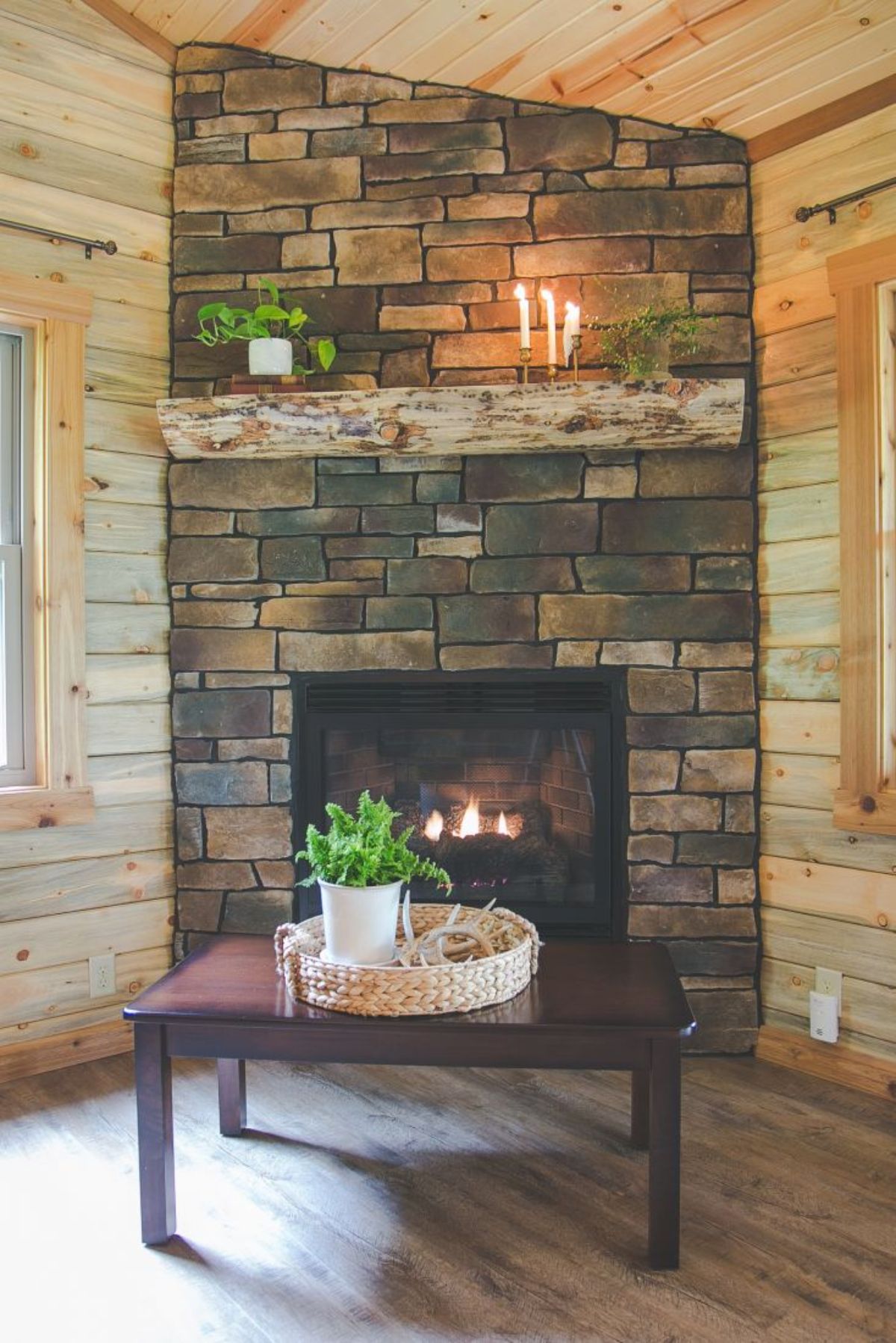 stone fireplace against log walls with dark wood coffee table in front of fire