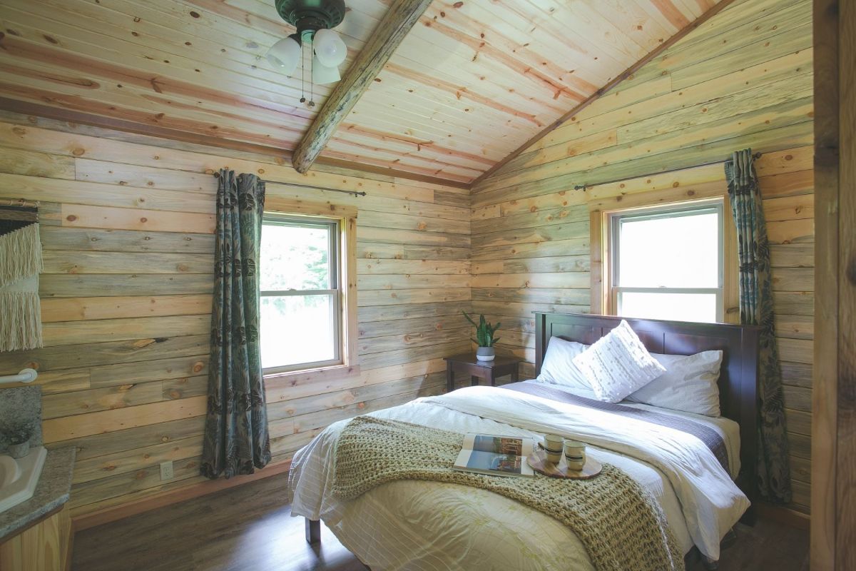 view of bed against wall in log cabin with white and gray linens