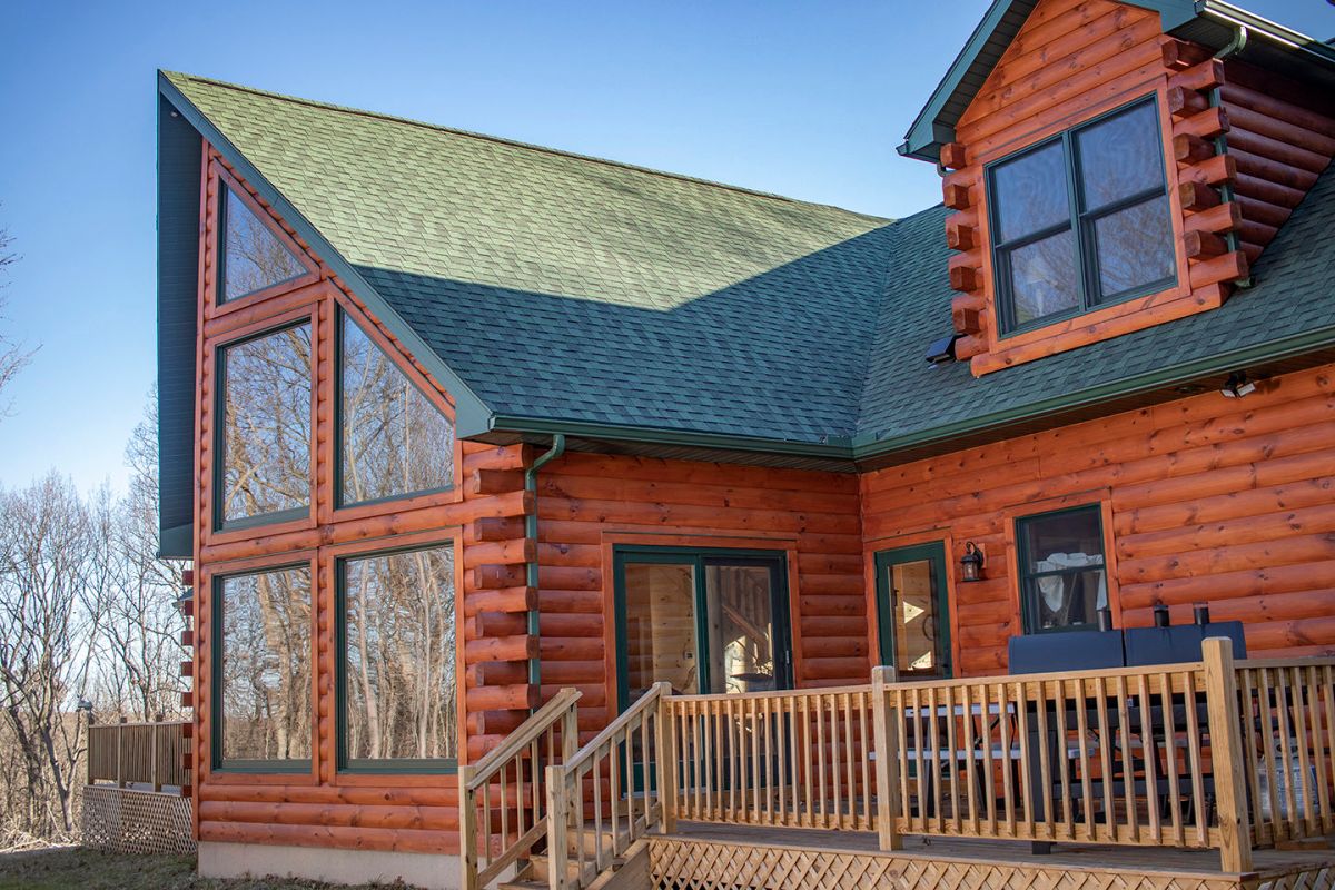 uncovered deck on side of log cabin with green roof and trim