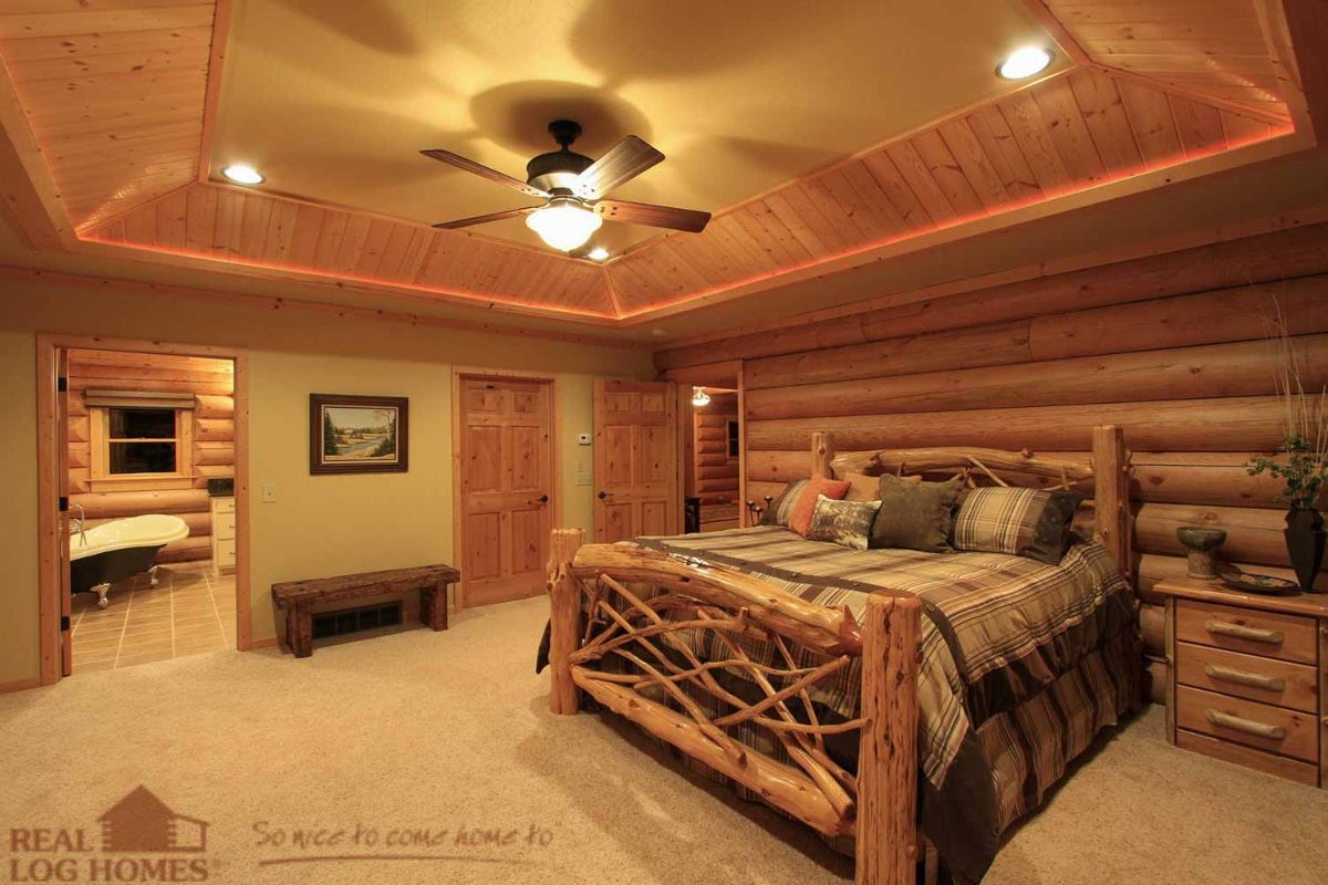 bed on right and open door to bathroom on left in log cabin
