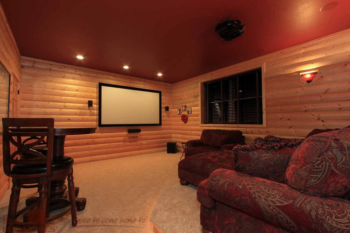 red leather sofas across from projector screen on log cabin wall