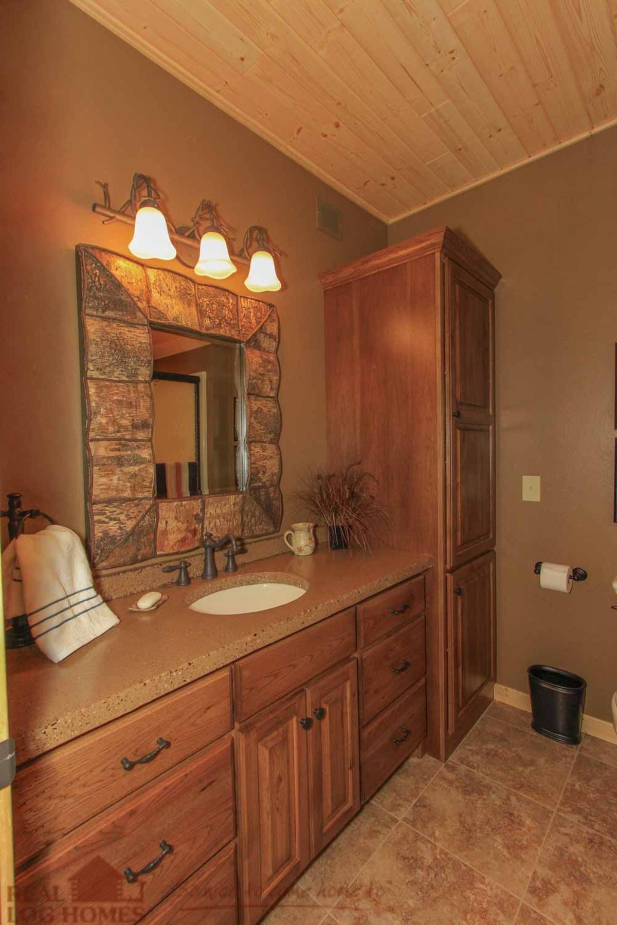 wood cabinets in bathroom with stone surrounding mirror