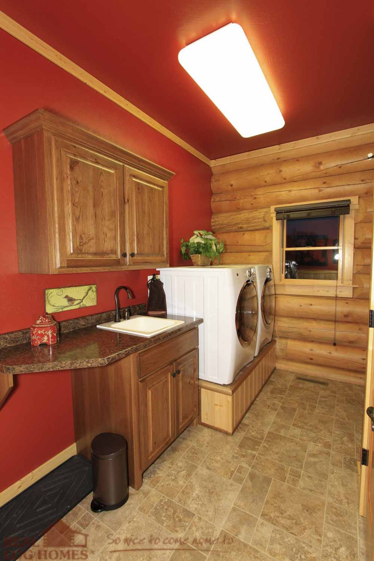 log cabin laundry room with white washer and dryer next to sink and red wall