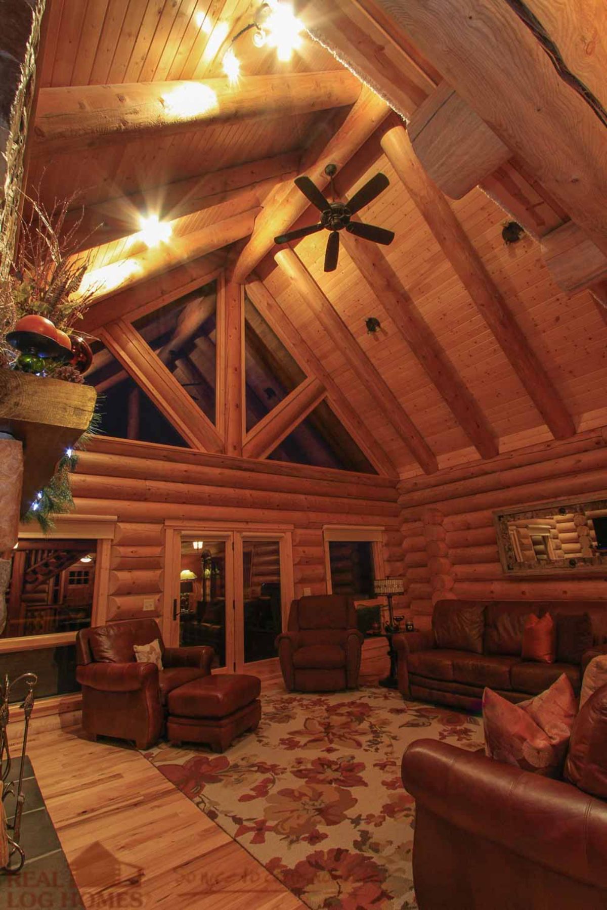 brown sofa and chairs in great room of log cabin with ceiling fan above