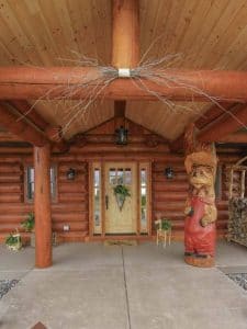 front door to the log cabin with a unique bear carving as a column support