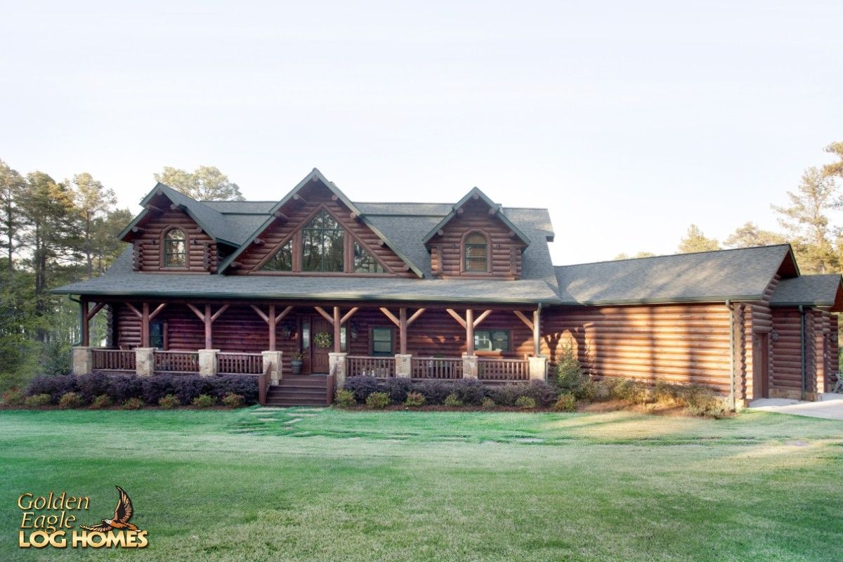 sprawling log cabin with covered porch and green lawn