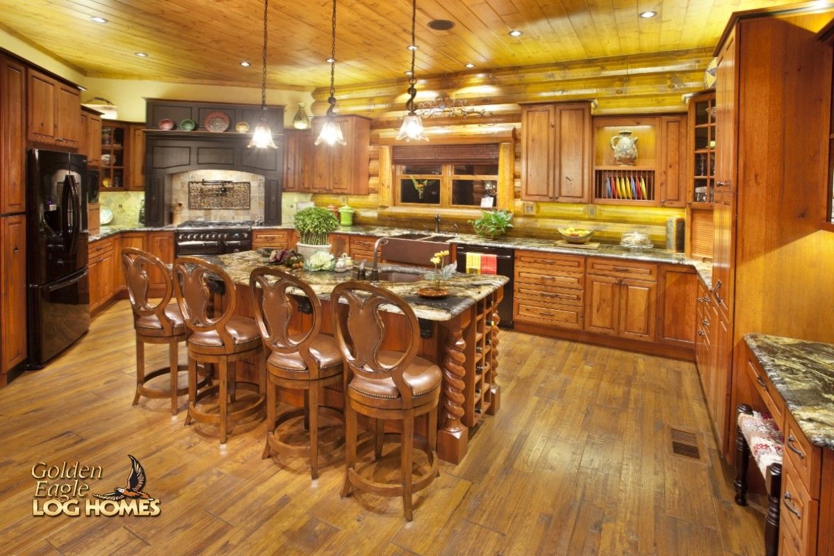 log home kitchen with dangling lights above bar and light wood cabinets