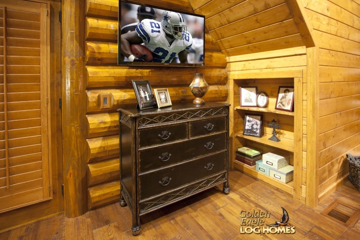 vintage chest of drawers against log wall beneath television