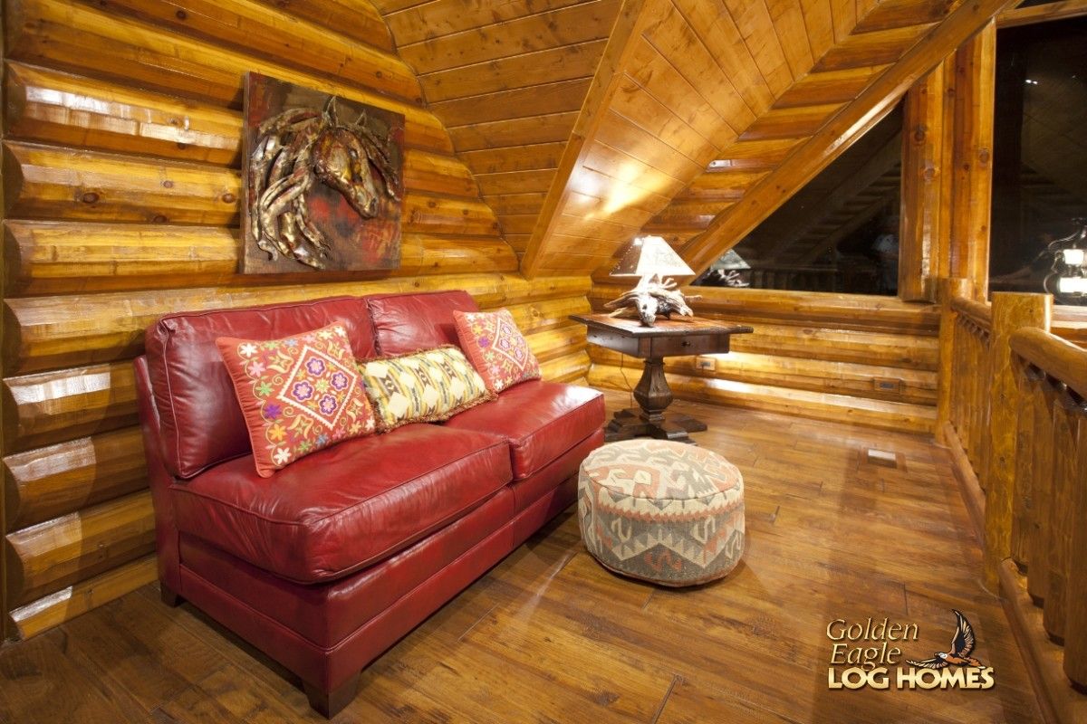 red leather sofa with white round ottoman in loft seating area of cabin