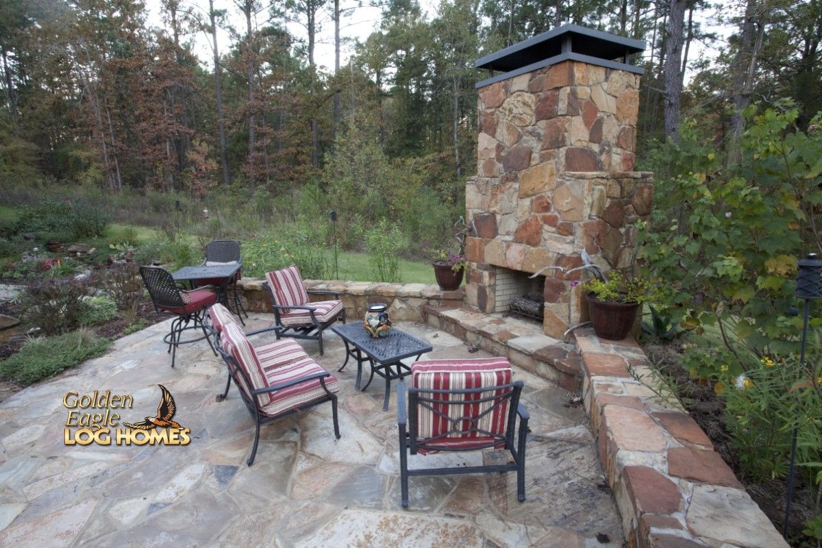 outdoor fireplace in open rock patio with striped chairs