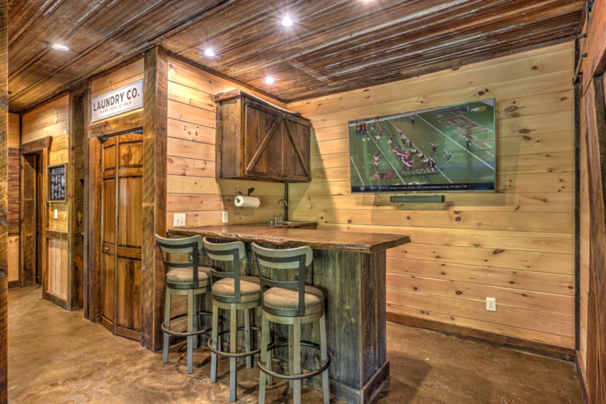 grey wood barstools and bar with TV in background