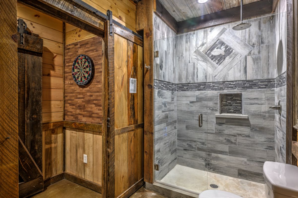 gray and white tile shower with dark wood walls on outside