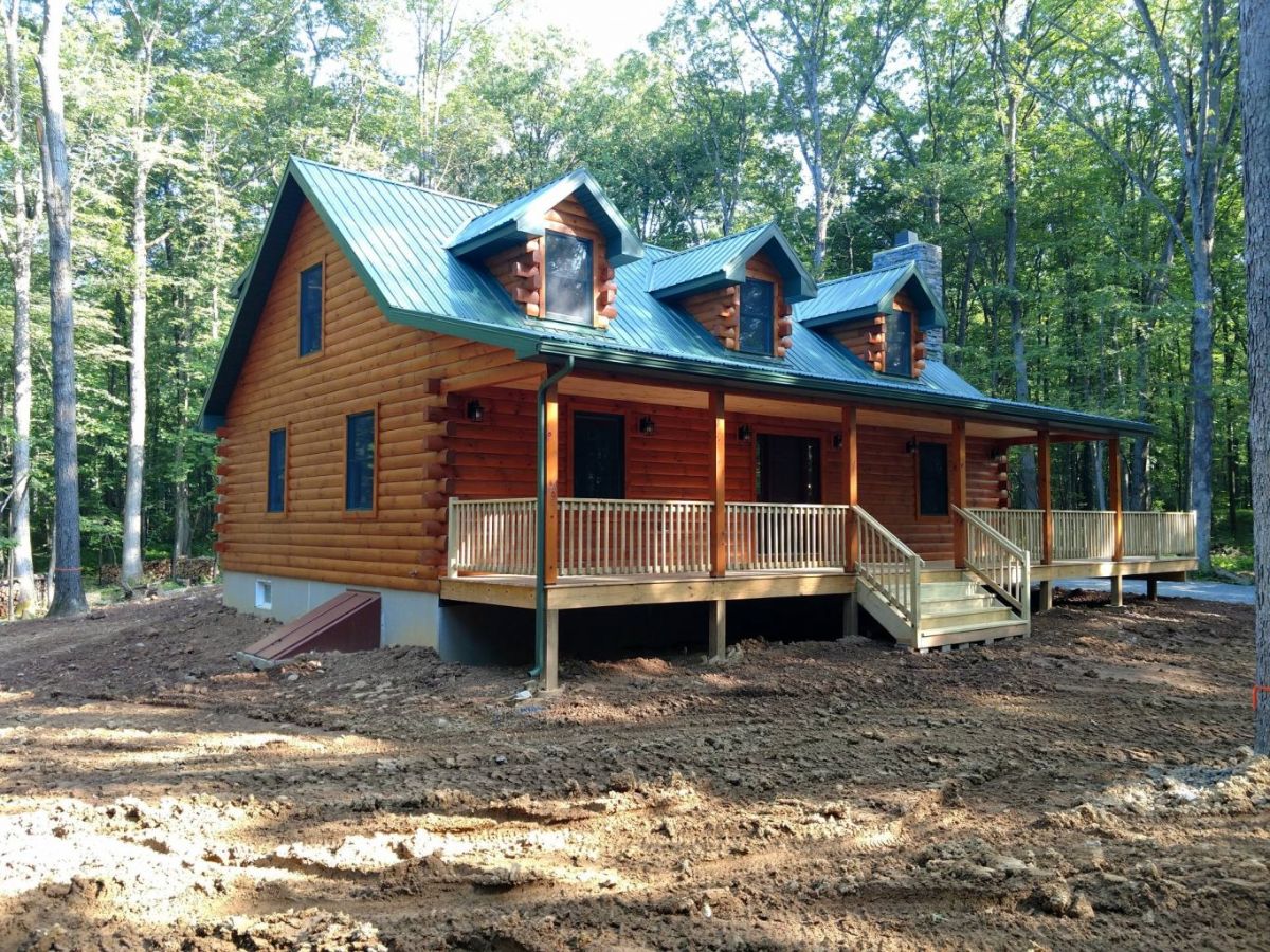 log cabin with green roof and covered porch