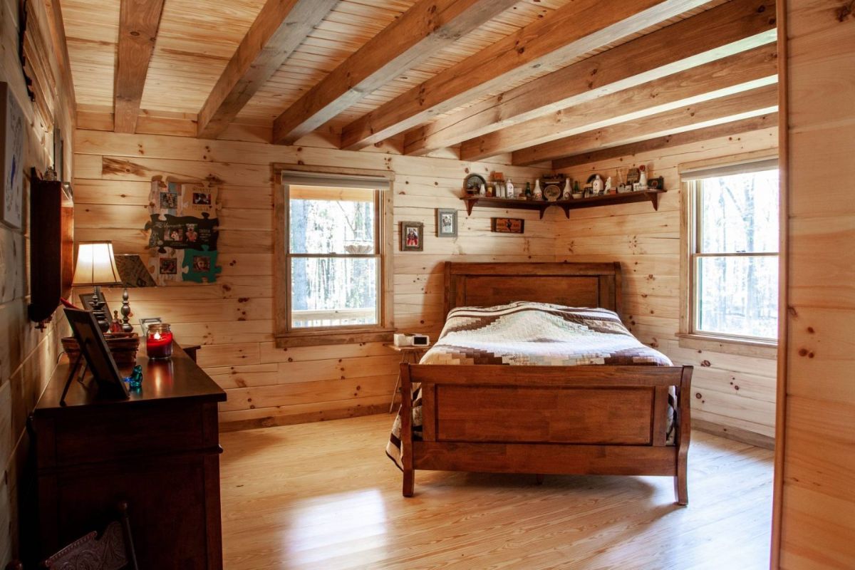 wood befdrame in corner of bedroom in log cabin with light wood walls