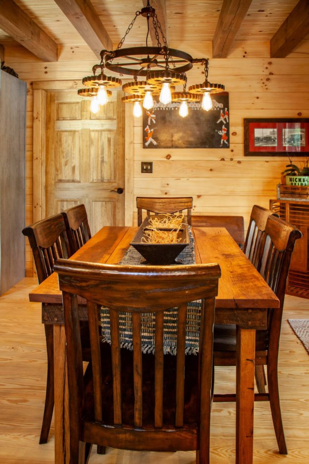 wood dining table beneath edison bulb light in log cabin