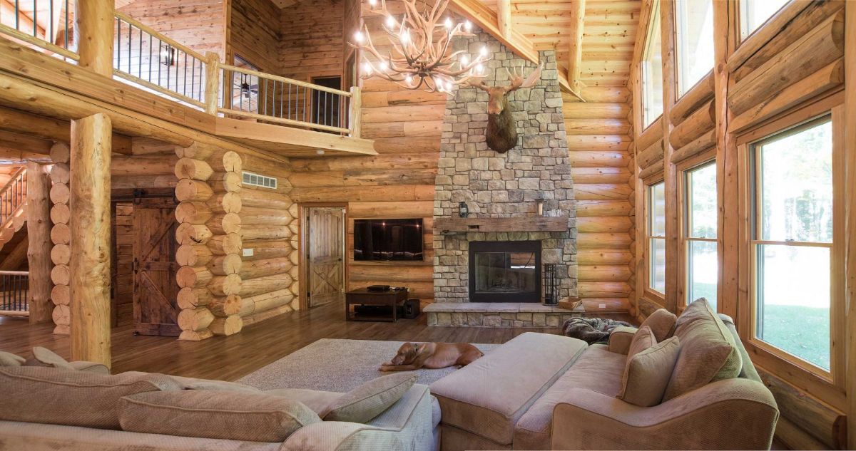 stone fireplace against wall in log cabin living room with light brown sofas