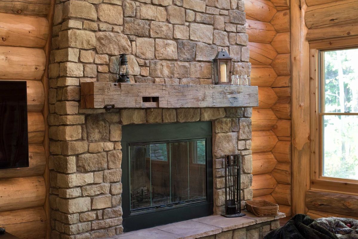 stone fireplace with black doors and log mantle