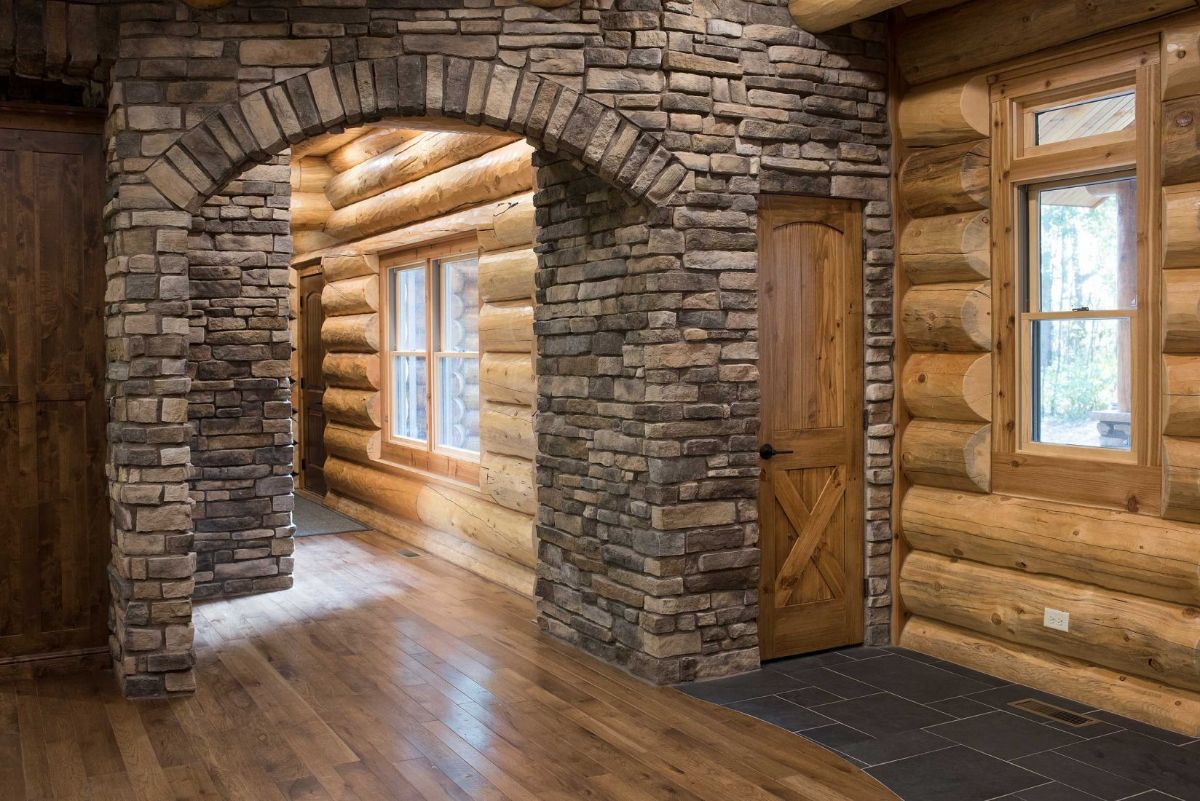 stone archway next to wood closet door in log cabin with round log walls