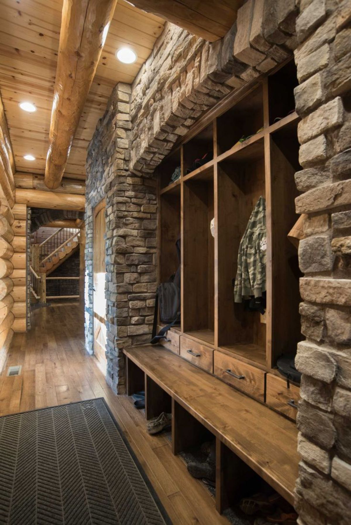 open closet storage in log cabin with wood shelves and stone surround