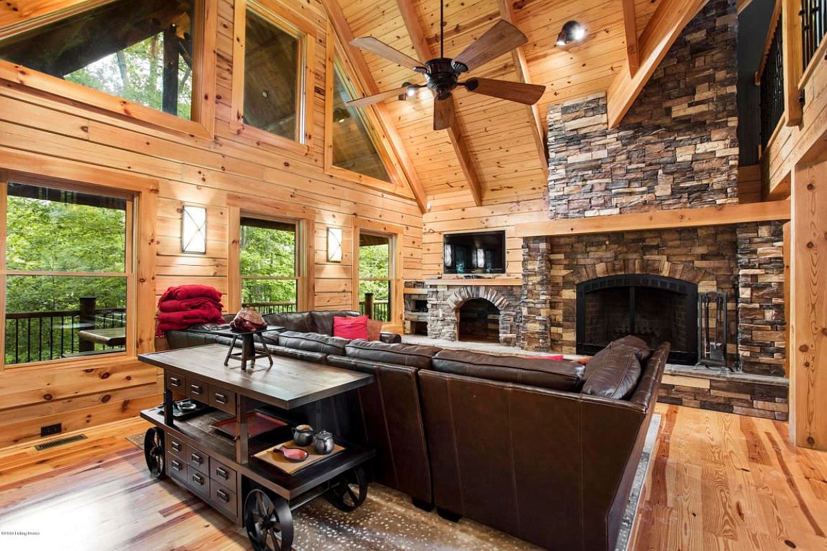 brown leather sectional sofa in front of stone fireplace with wall of windows to left