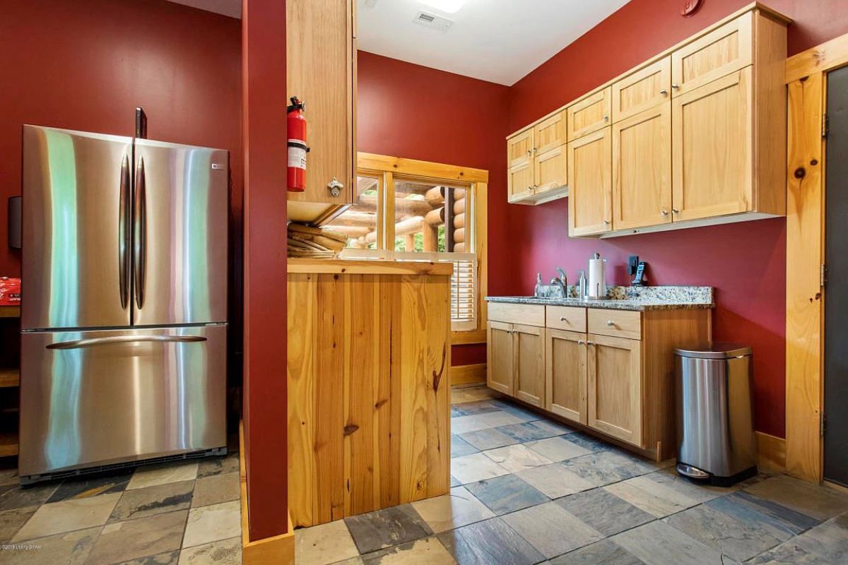 dark red painted walls with pine wood cabinets in laundry room on right with refrigerator on left
