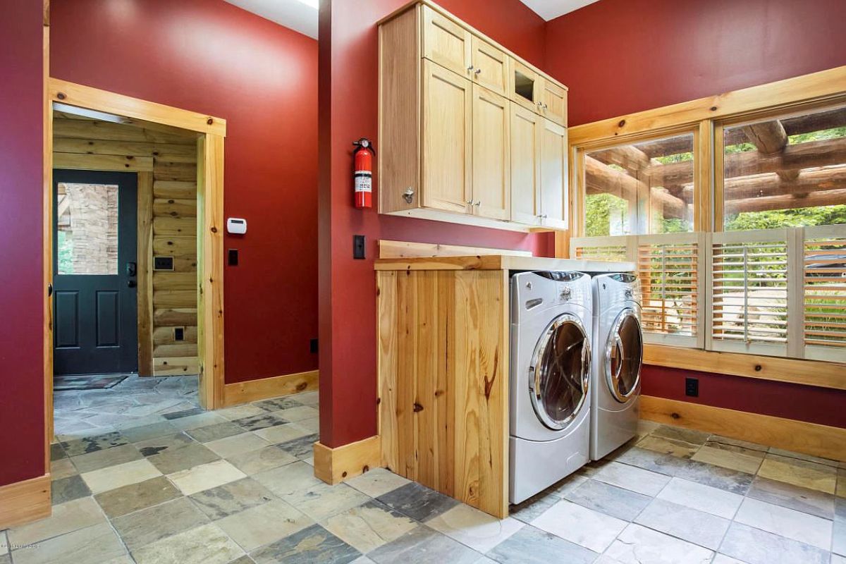 stainless steel laundry units under light wood cabinets with dark red wall background