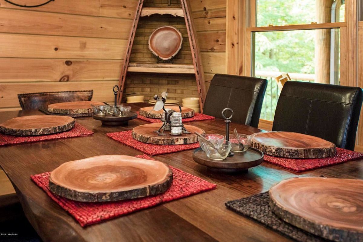 dark wood dining table with high backed leather chairs and round wood slice plates at place settings